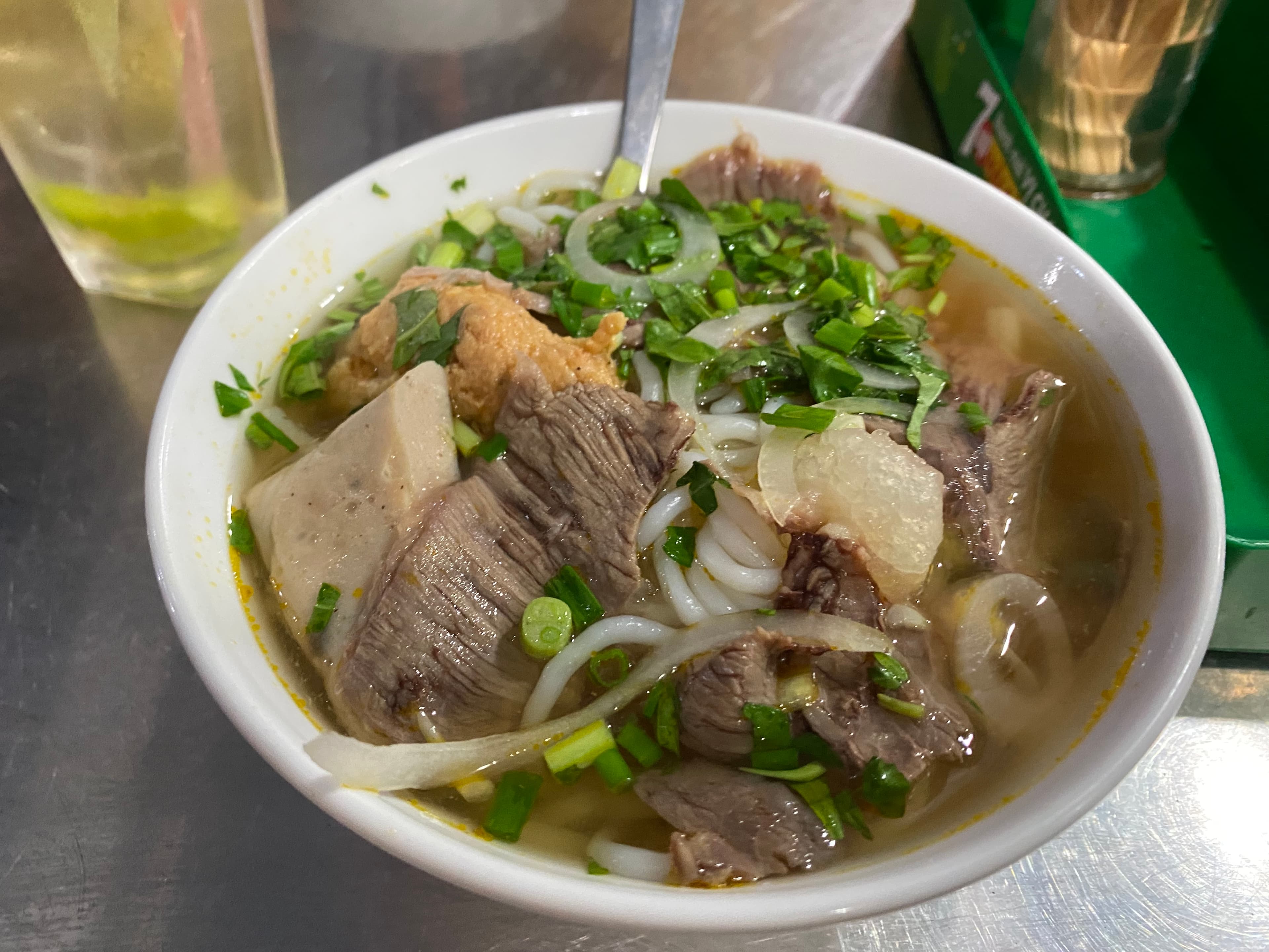 Bowl of pho bo with beef, rice noodles, onions, and herbs