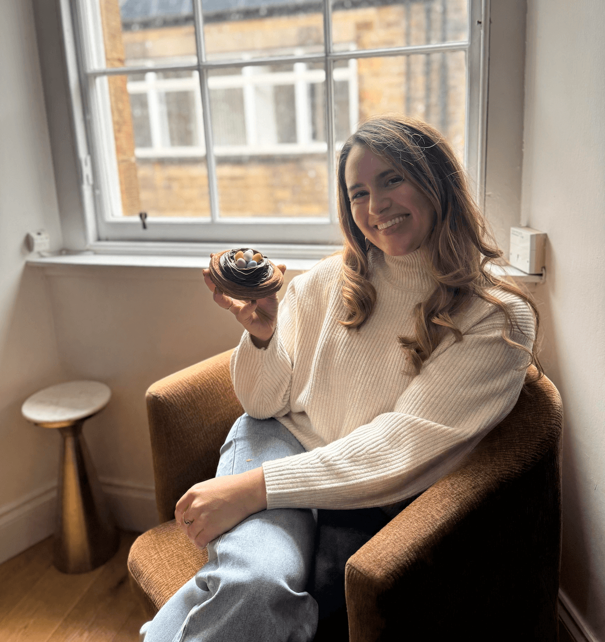 Sarah smiling with a small dessert by a window
