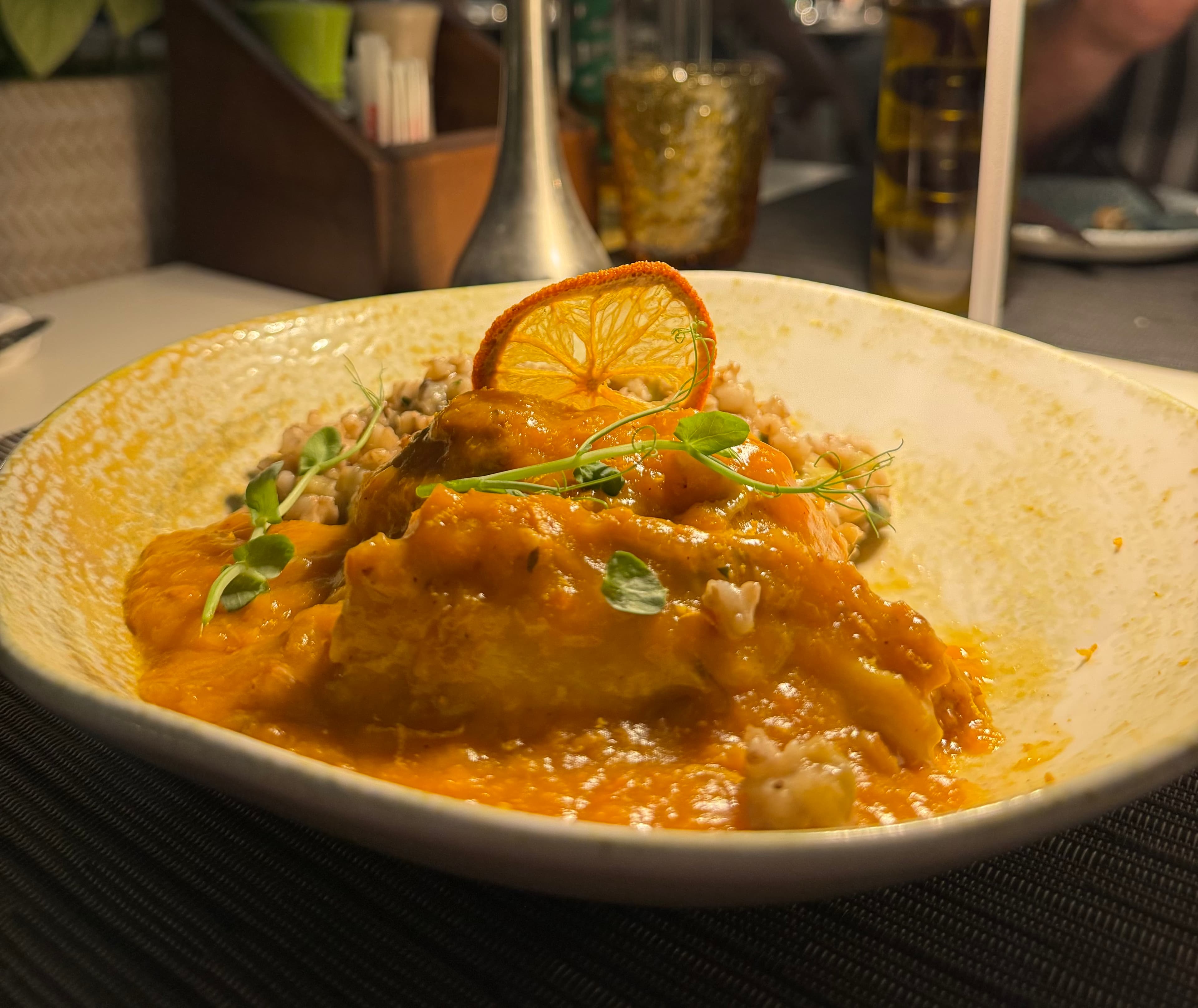 Capon plated with orange-toned sauce and grains in Dubrovnik