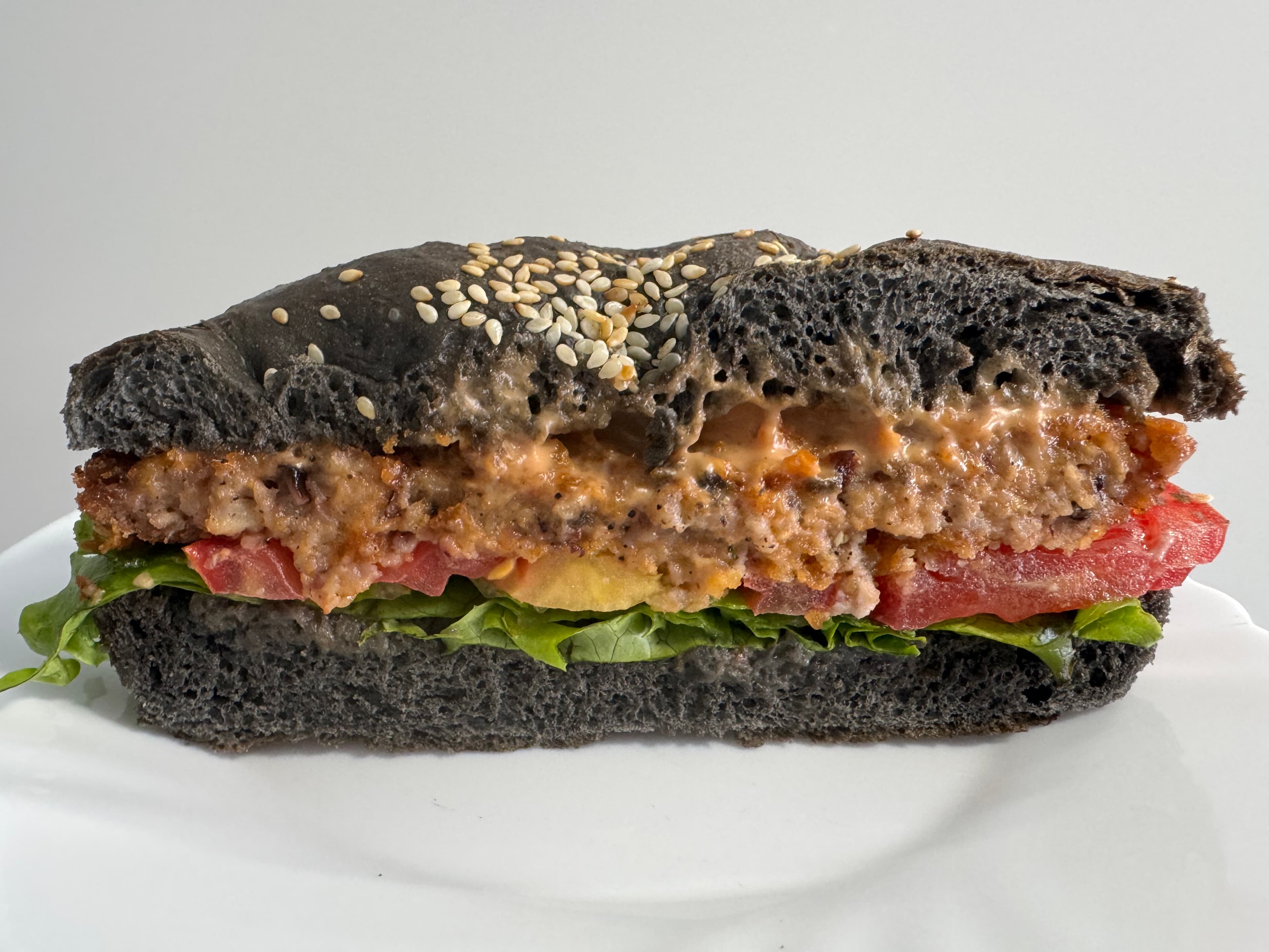 Octopus burger served on a black bun with lettuce and tomato