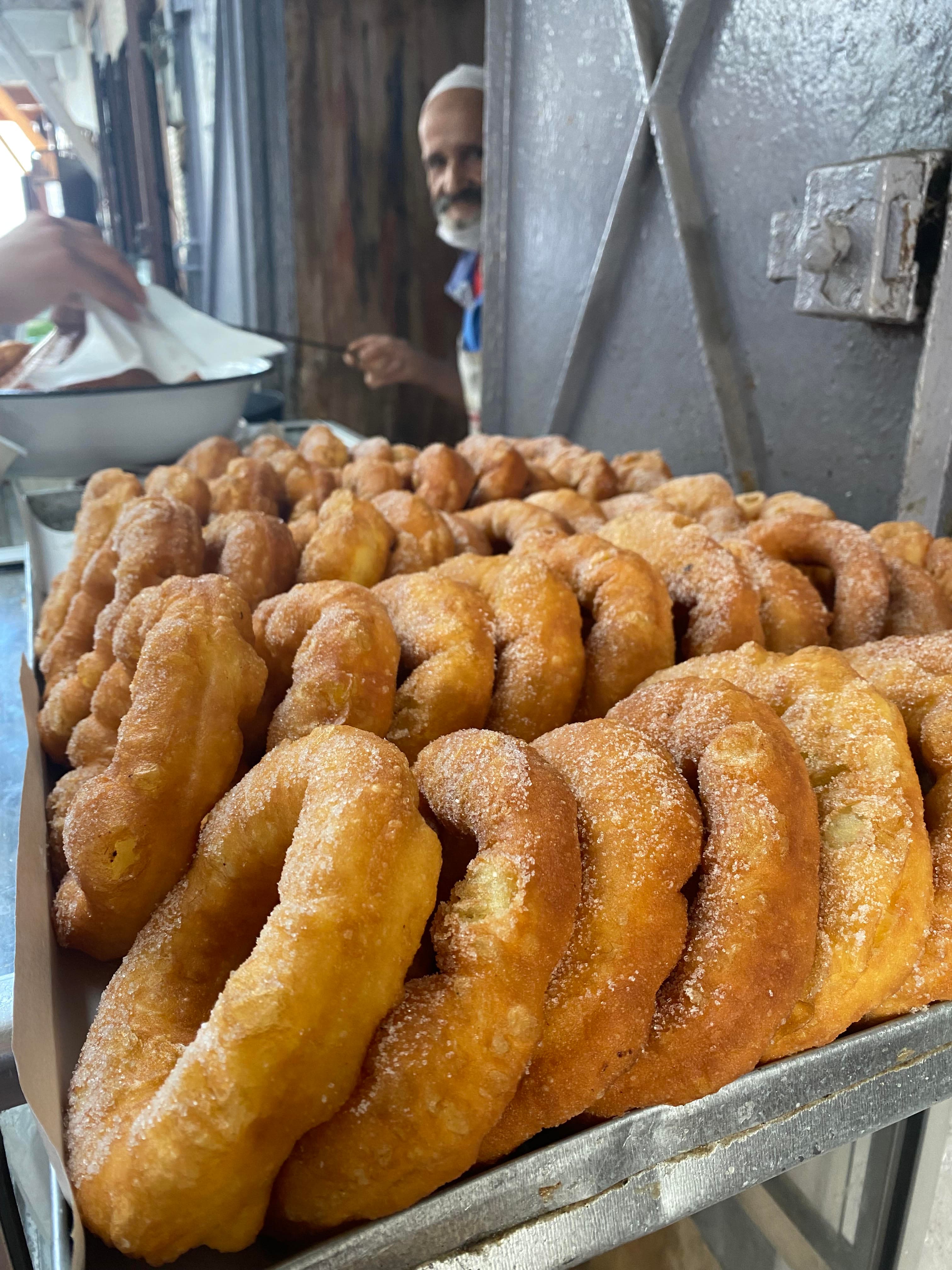 Freshly fried svenj stacked at a Marrakesh market stall