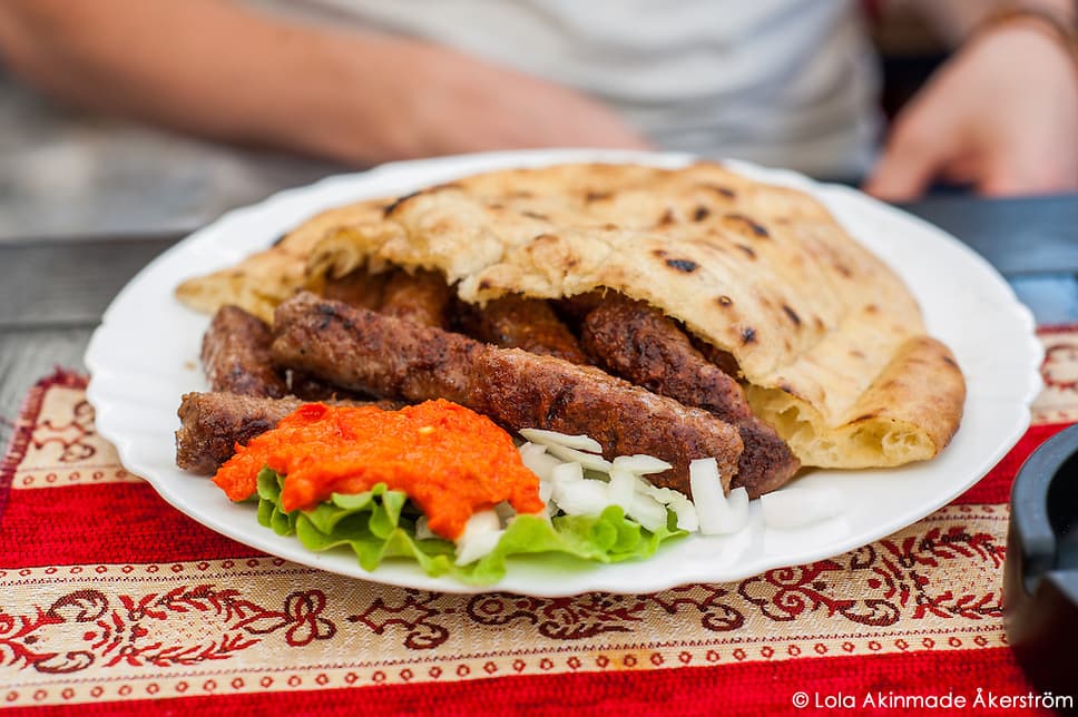 Plate of cevapi with flatbread, onions, and red pepper spread in Mostar
