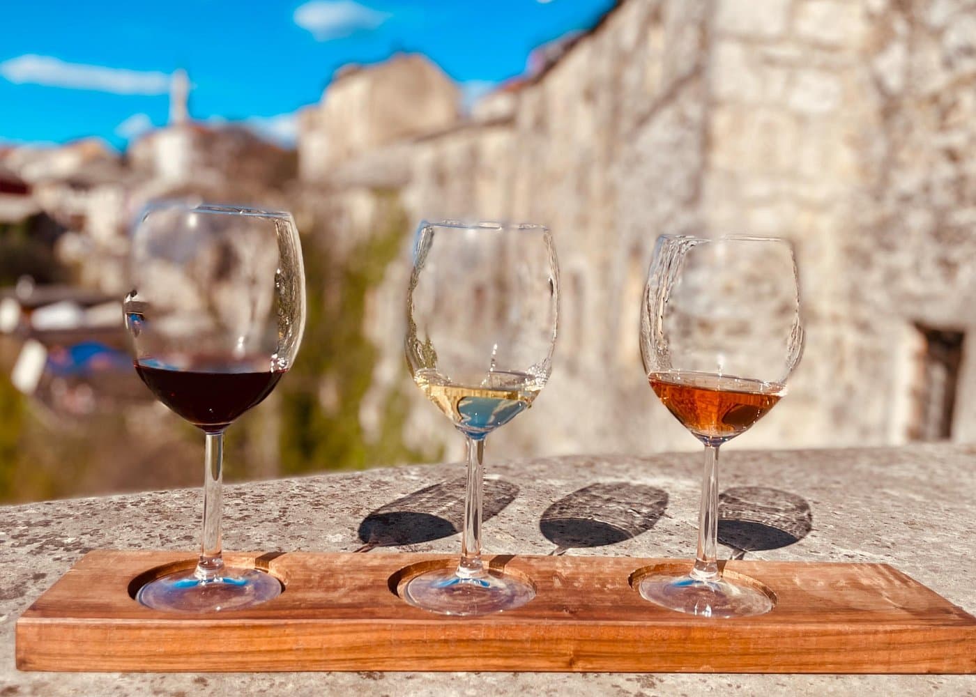 Three glasses of Herzegovinian wine overlooking stone buildings in Mostar