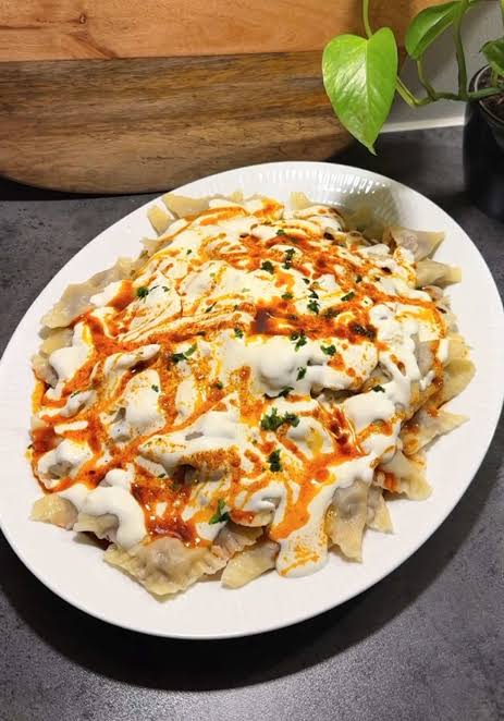 Plate of klepe dumplings covered in creamy sauce and paprika oil