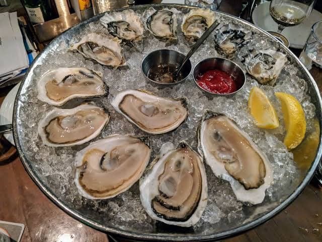 Fresh oysters served on ice with lemon wedges and dipping sauces
