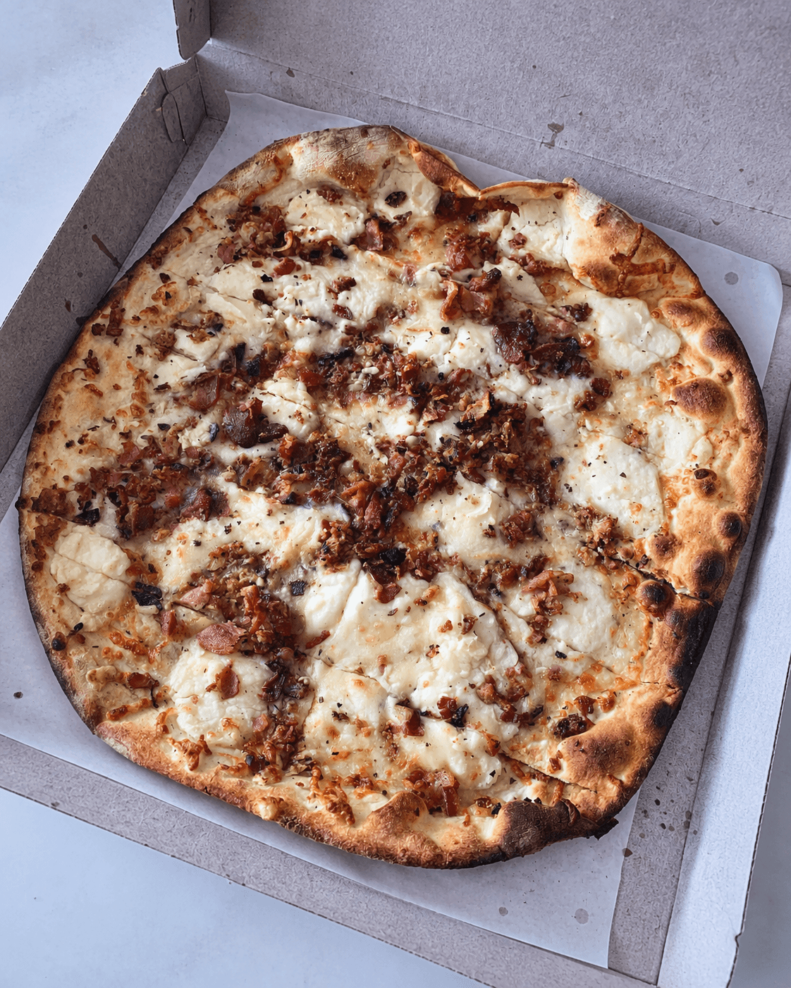 New Haven mashed potato pizza topped with mashed potatoes, cheese, bacon, and herbs