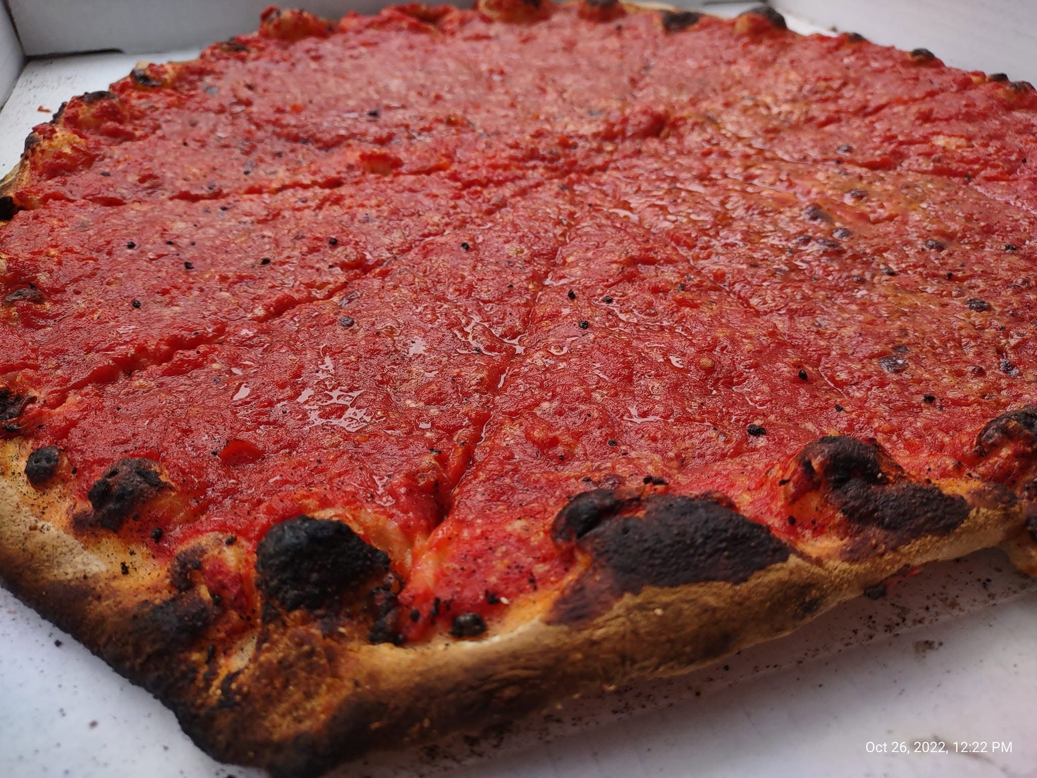 New Haven tomato pie topped with tomato sauce, grated cheese, and oregano
