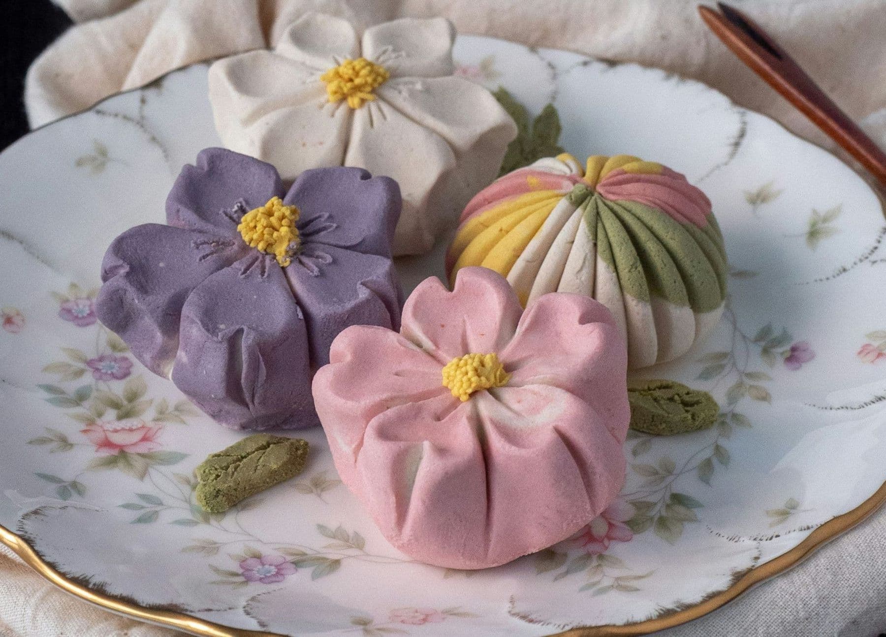 White and pink floral-shaped wagashi sweets on a floral ceramic plate