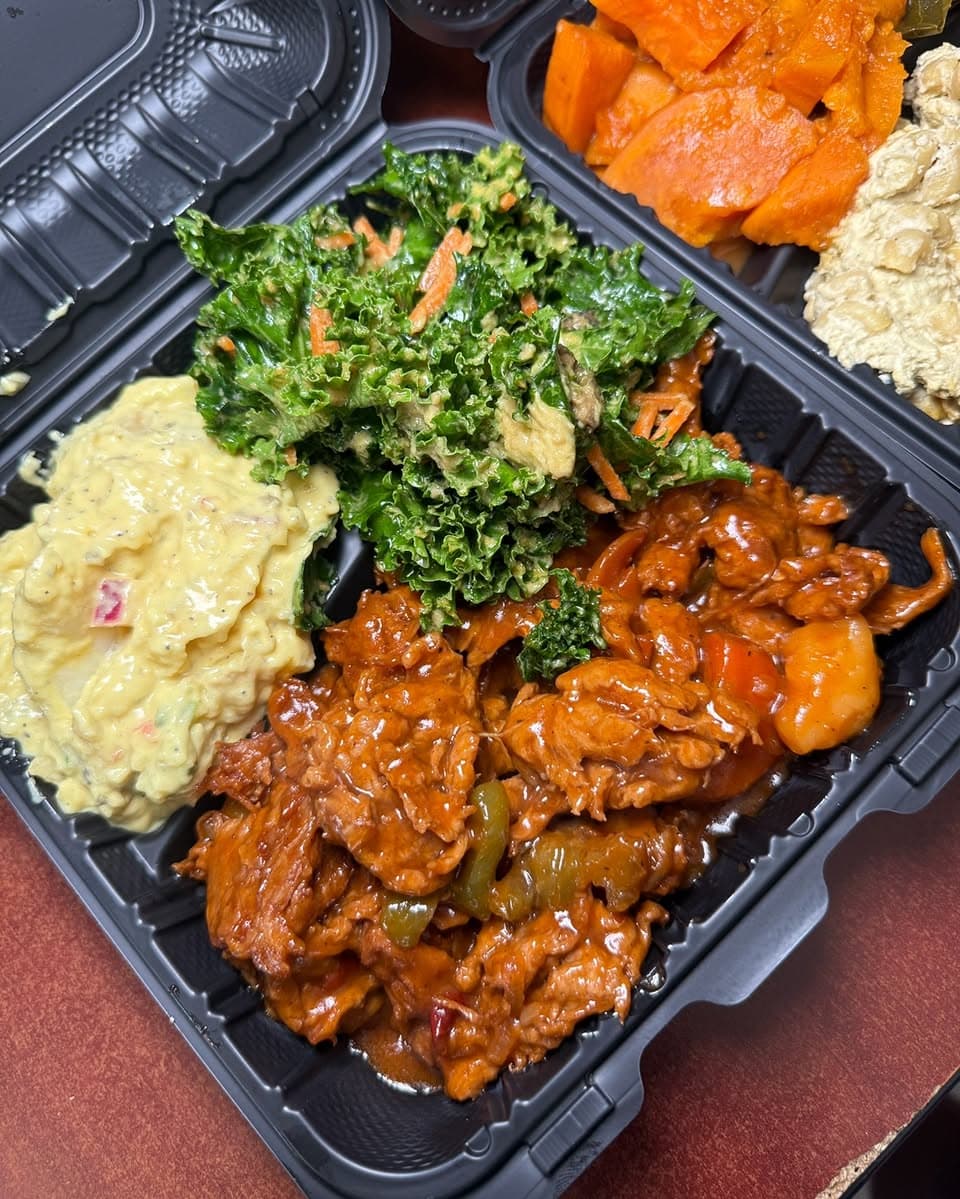 Baltimore soul food takeout plate with greens, yams, salad, and sauced meat