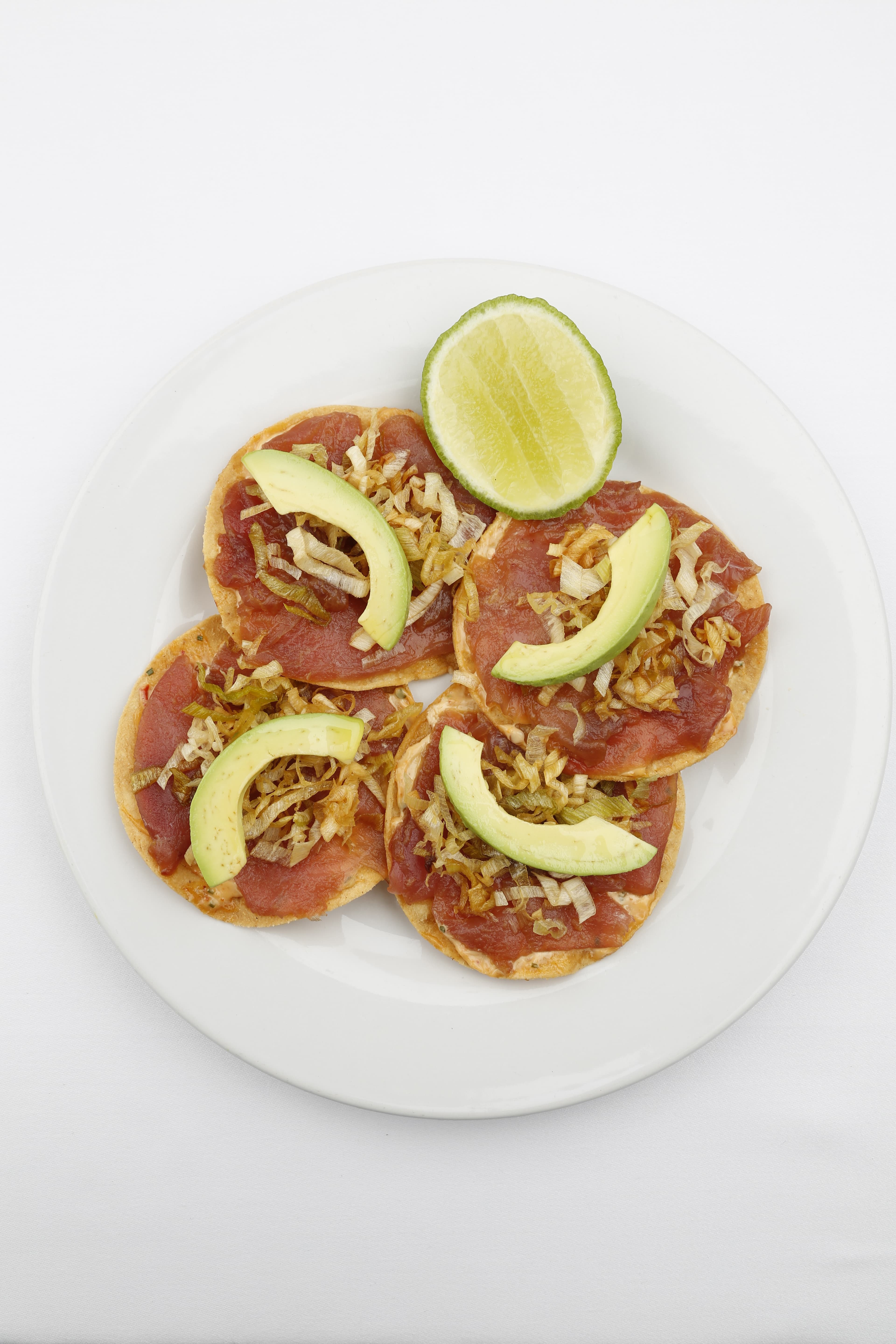 Contramar-style tuna tostada topped with sauce and sliced tuna