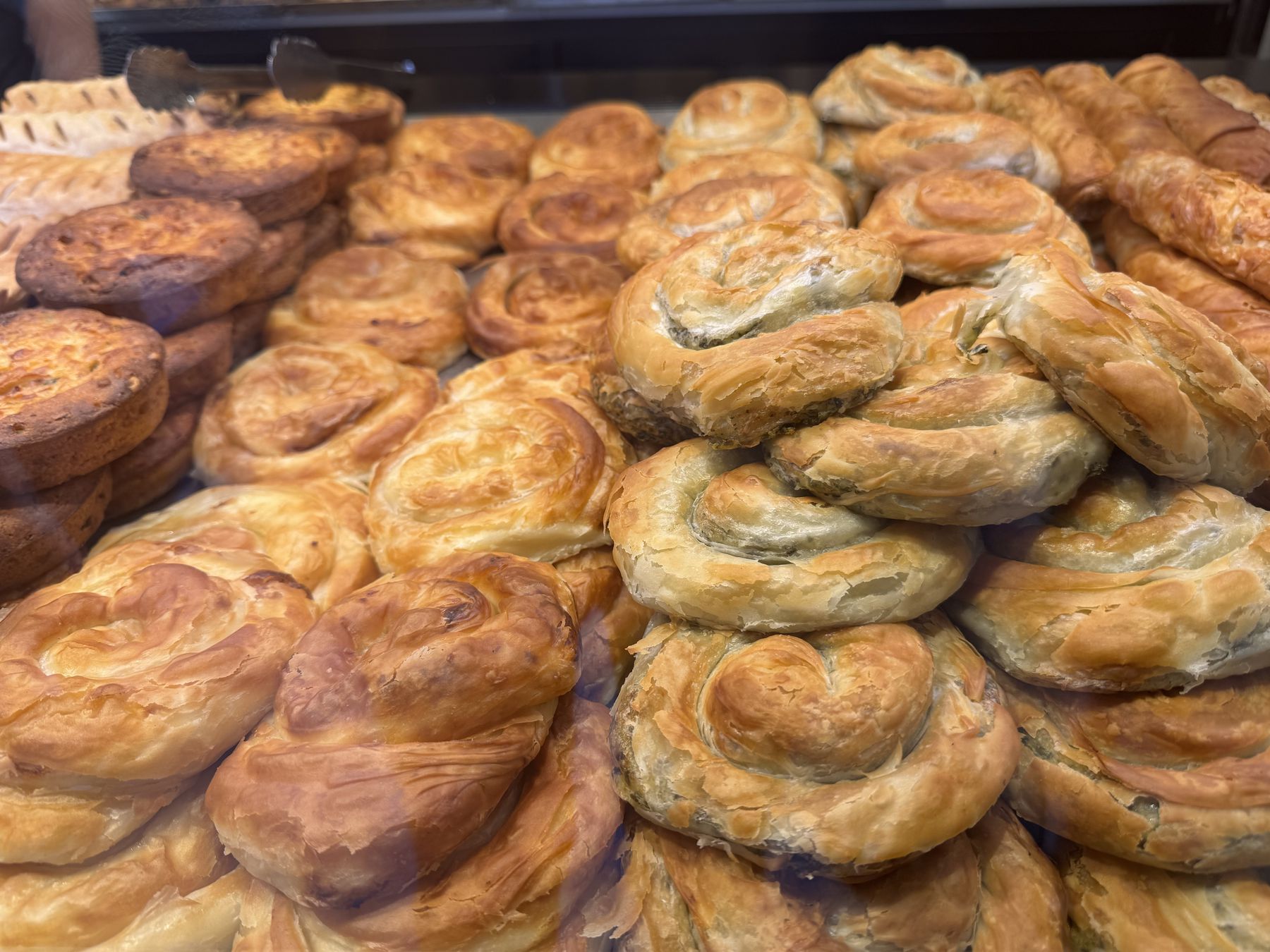Freshly baked spinach borek pastries displayed in a bakery case
