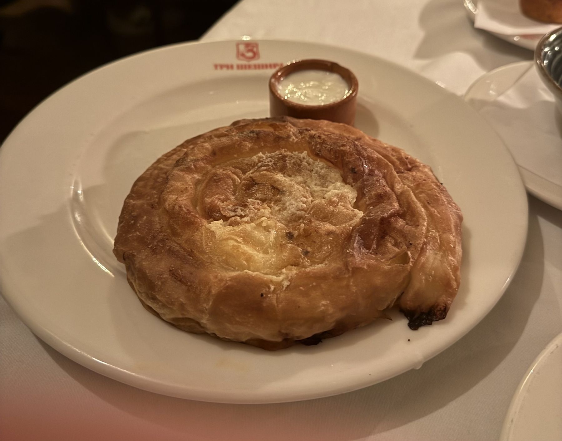 Traditional Serbian pie served warm on a plate with a small cup of dairy sauce