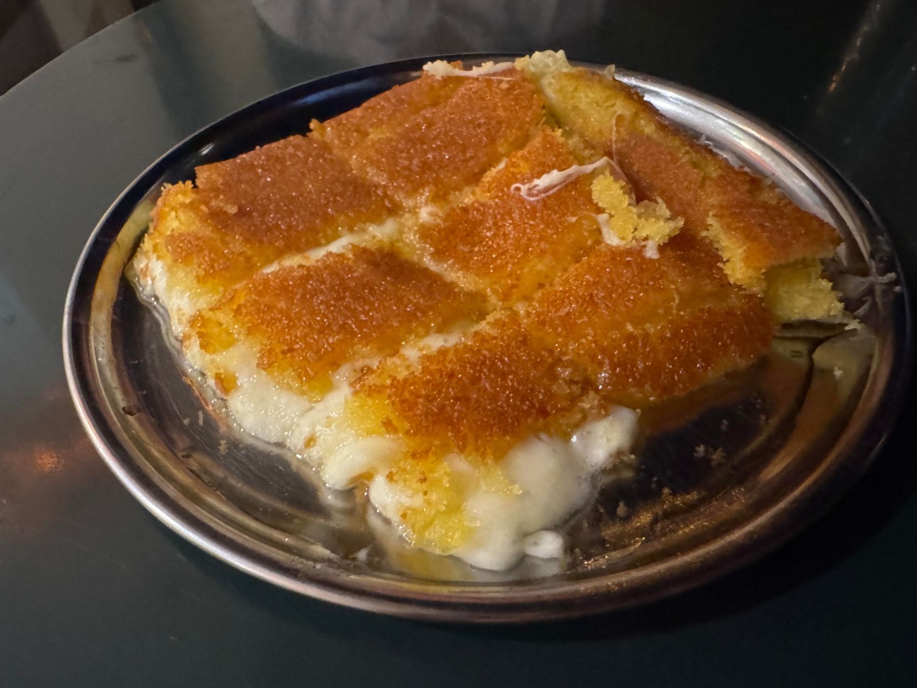 Kunefe dessert sliced into pieces on a metal plate