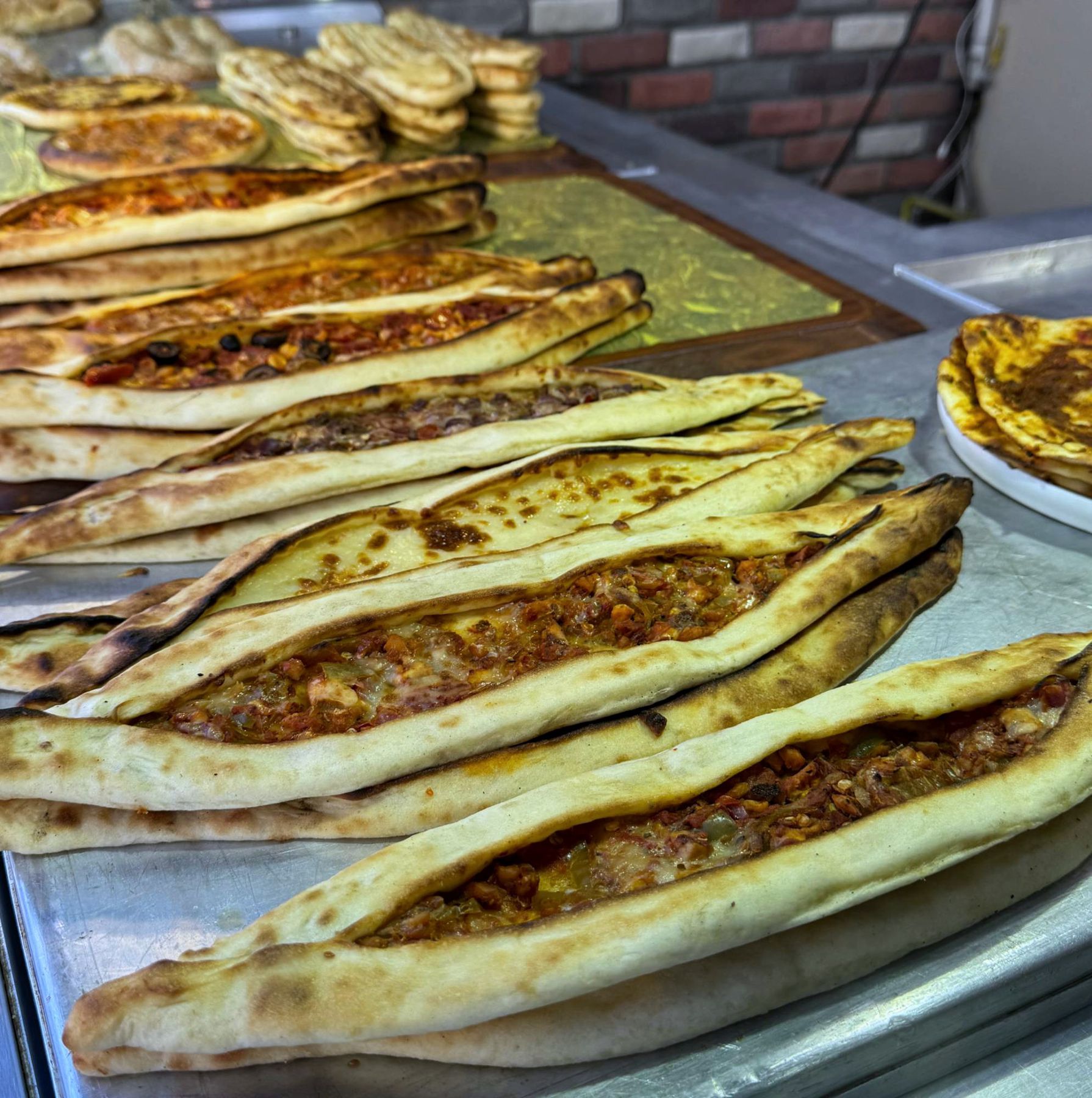 Rows of Turkish pide flatbread with cheese and meat toppings