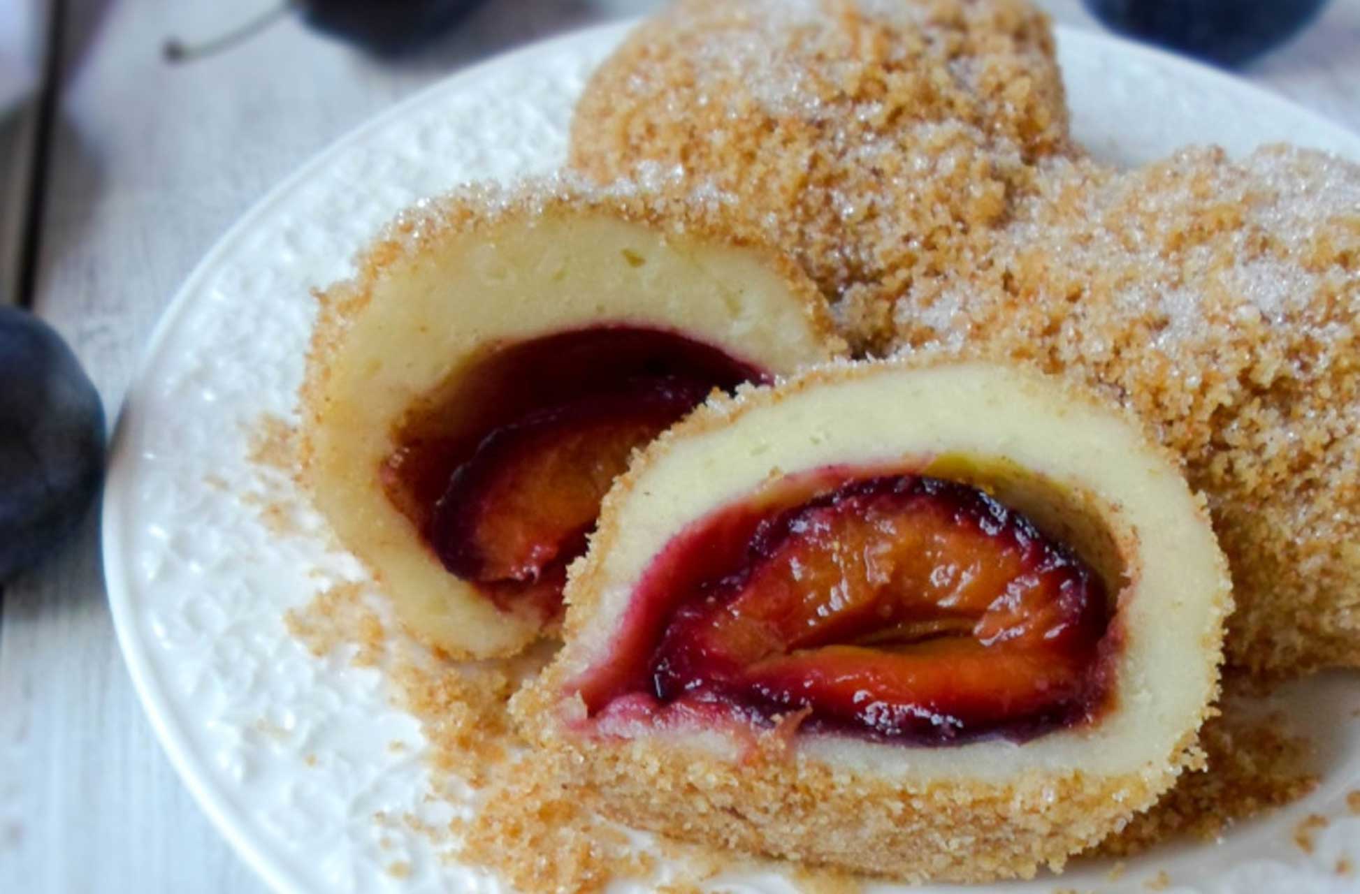 Knedle sa šljivama cut open to show the plum filling inside breadcrumb-coated dumplings