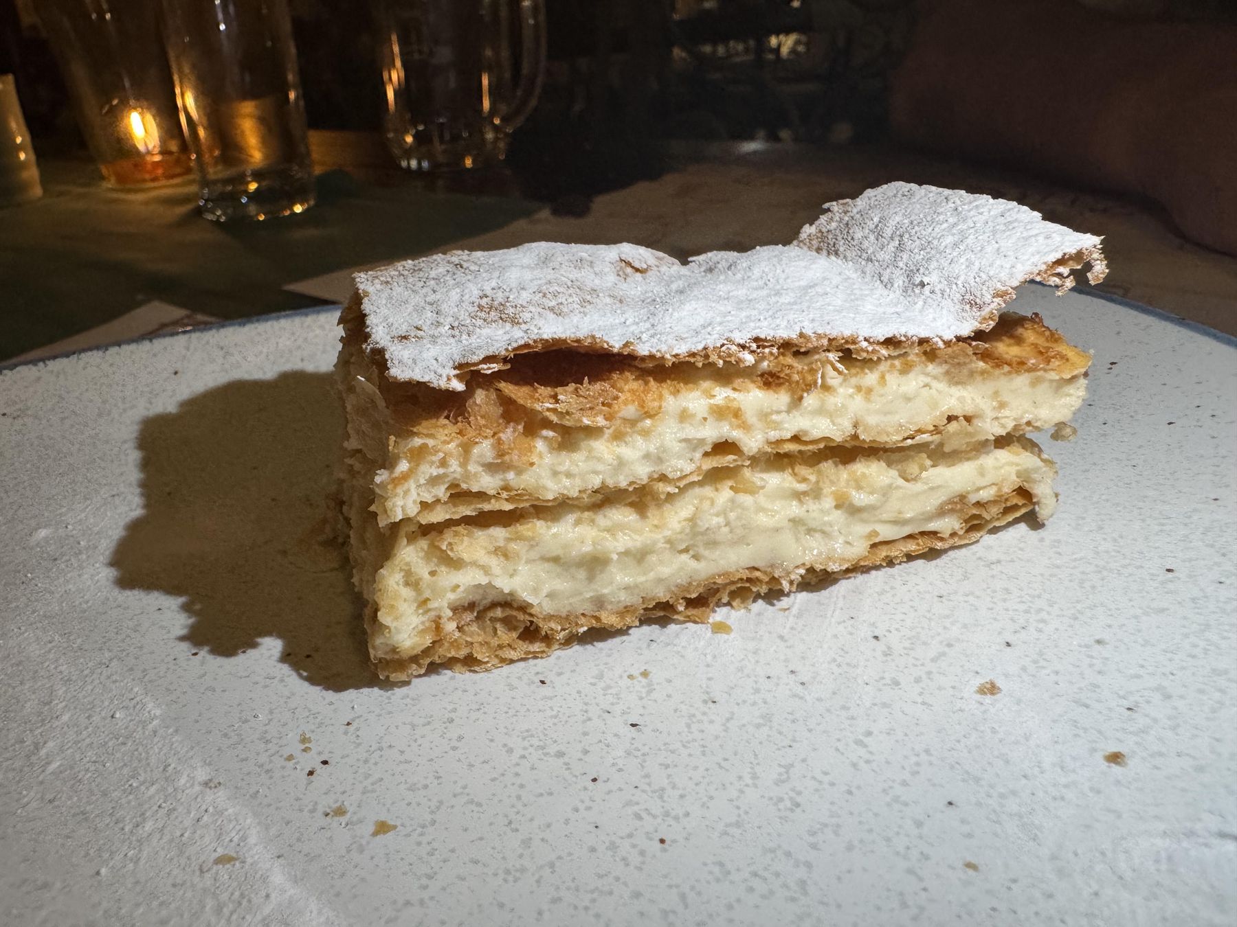 Slice of Krempita dusted with powdered sugar on a plate in Kotor